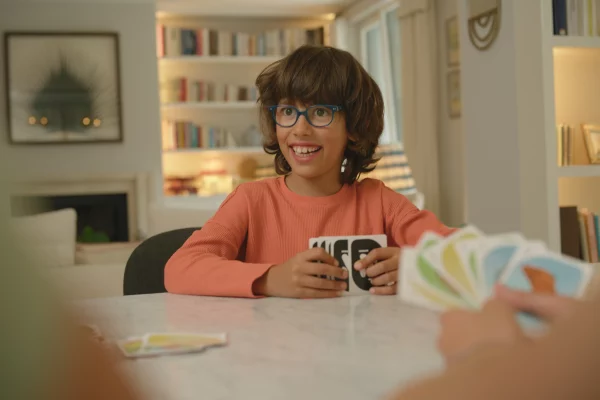 Un enfant assis jouant au jeu de cartes Nutrino, découvrant la nutrition de façon ludique