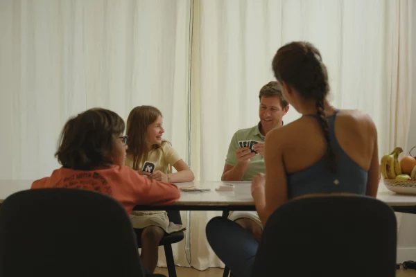 Une famille avec mère, père, fille et fils jouant au jeu de cartes Nutrino à la maison, apprenant la nutrition de façon ludique