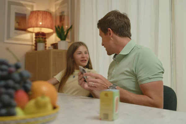 Un père et sa fille jouent ensemble au jeu de cartes Nutrino à la maison, autour de la table